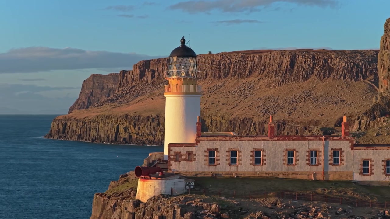 Splendida luce mattutina che illumina l'iconico faro di Neist Point sull'isola di Skye. Un paesaggio scozzese mozzafiato con scogliere imponenti.