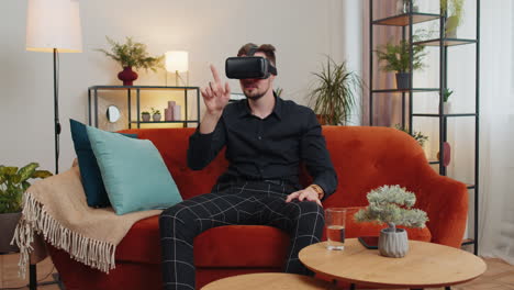 joven usa gafas de realidad virtual en casa juega videojuegos en 3d haciendo gestos con las manos