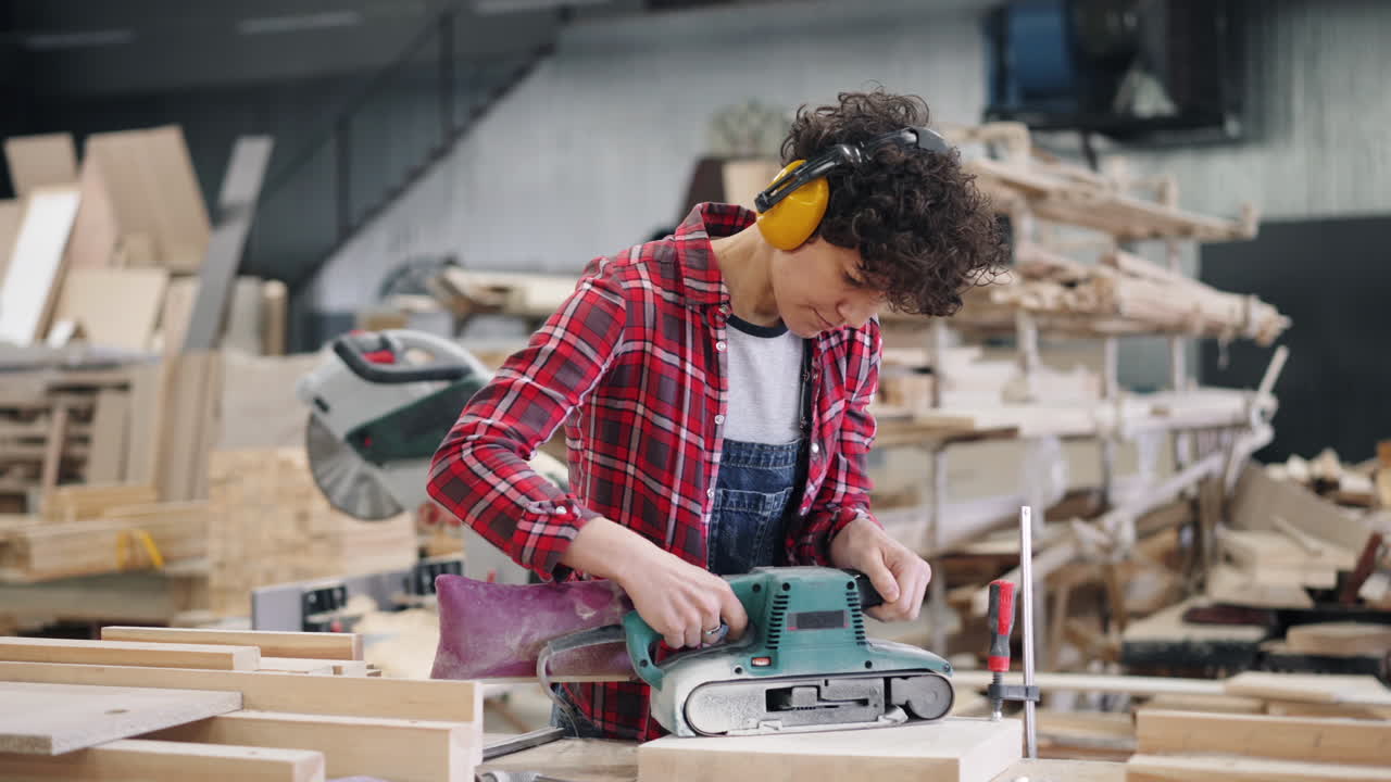 Woman Working with a Belt Sander in a Workshop