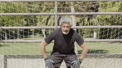 front view of a focused senior goalkeeper defending the soccer goal