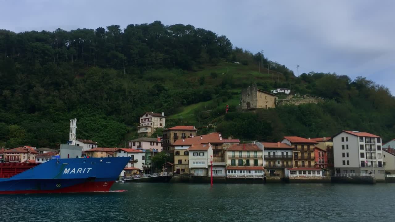 The cargo ship "Marit" gracefully enters the picturesque Pasaia Bay with San Juan town in the background. iBasque Country, Spain.
