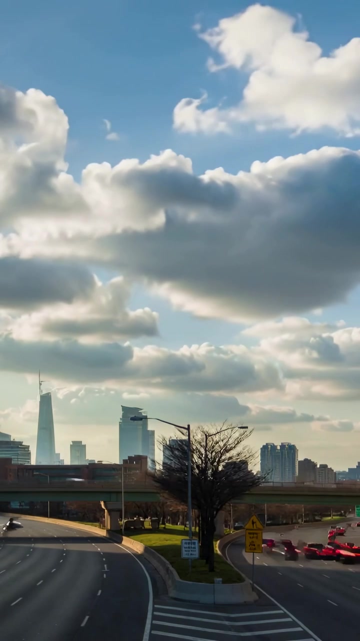 Video verticale: Nuvole cumulo che si muovono sopra lo skyline della città, auto in coda sulla rampa di uscita dell'autostrada.