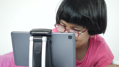 Child-girl-using-digital-tablet-sitting-on-a-table