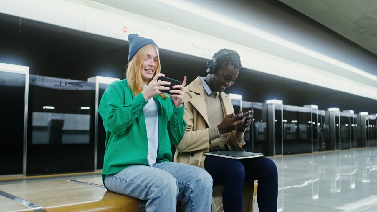 Young People Playing Mobile Games at Subway Station