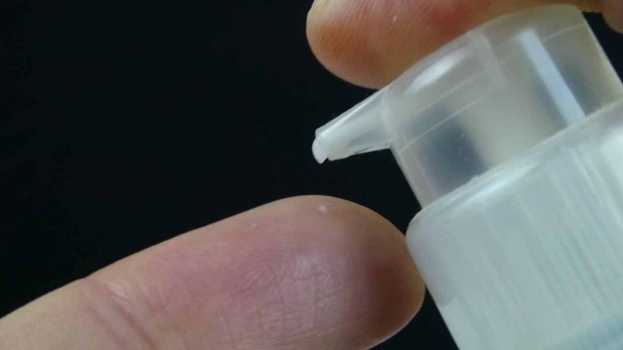 video en primer plano que muestra una crema de lujo siendo dispensada desde una botella sin aire en un dedo, capturado en detalle ultra-macro