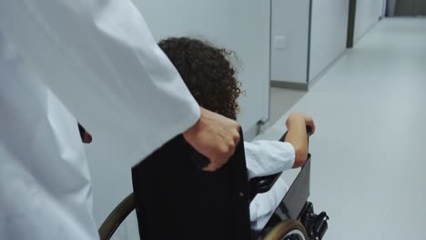 close-up of caucasian male doctor pushing pushing african american boy in wheelchair in hospital 4k