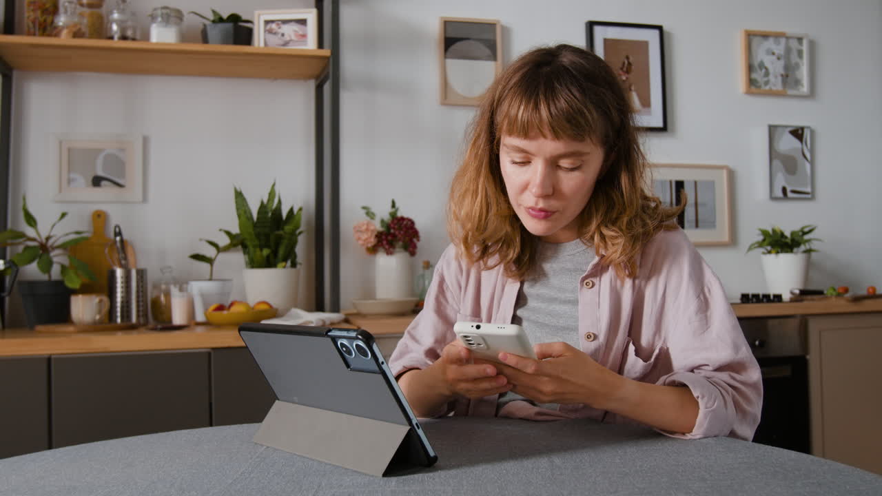 Woman using tablet and phone in the kitchen