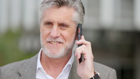 a mature man talking on a mobile phone outdoors