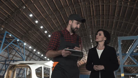 businesswoman and mechanic discussing in a warehouse