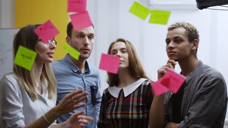 colleagues brainstorming standing next to glass wall, give the explanation