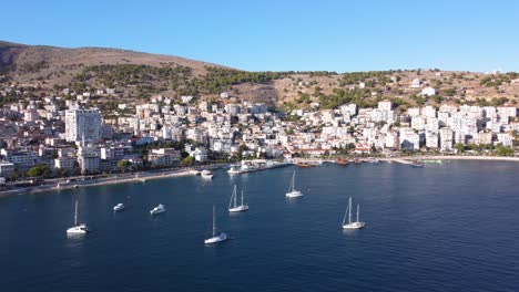 AERIAL-Side-Panning-Shot-of-Sarande,-Albania-and-its-Bay