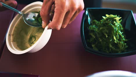 A-professional-chef-prepares-a-traditional-Japanese-dish-with-seaweed,-a-poke-bowl,-in-a-showcooking-spectacle