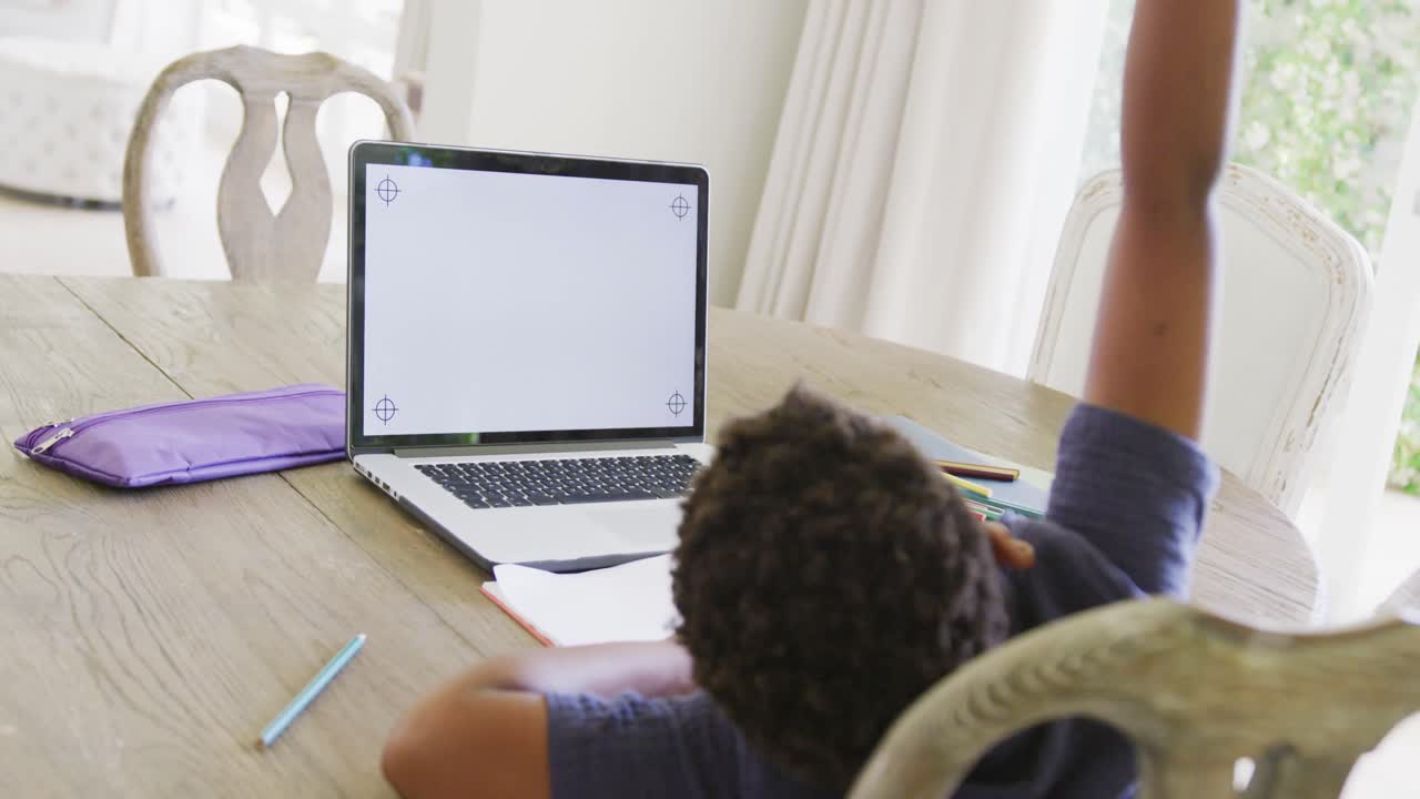 Happy african american boy using laptop for online lesson with copy space, in slow motion