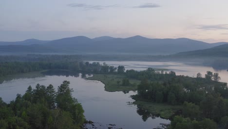 Spectacular-aerial-view-flying-over-scenic-lake-covered-in-fog-at-dawn