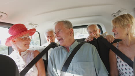 group of senior friends sitting in back of people carrier being driven to vacation