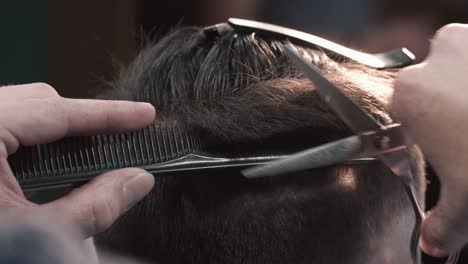 close-up of a professional barber giving a haircut with comb and scissors