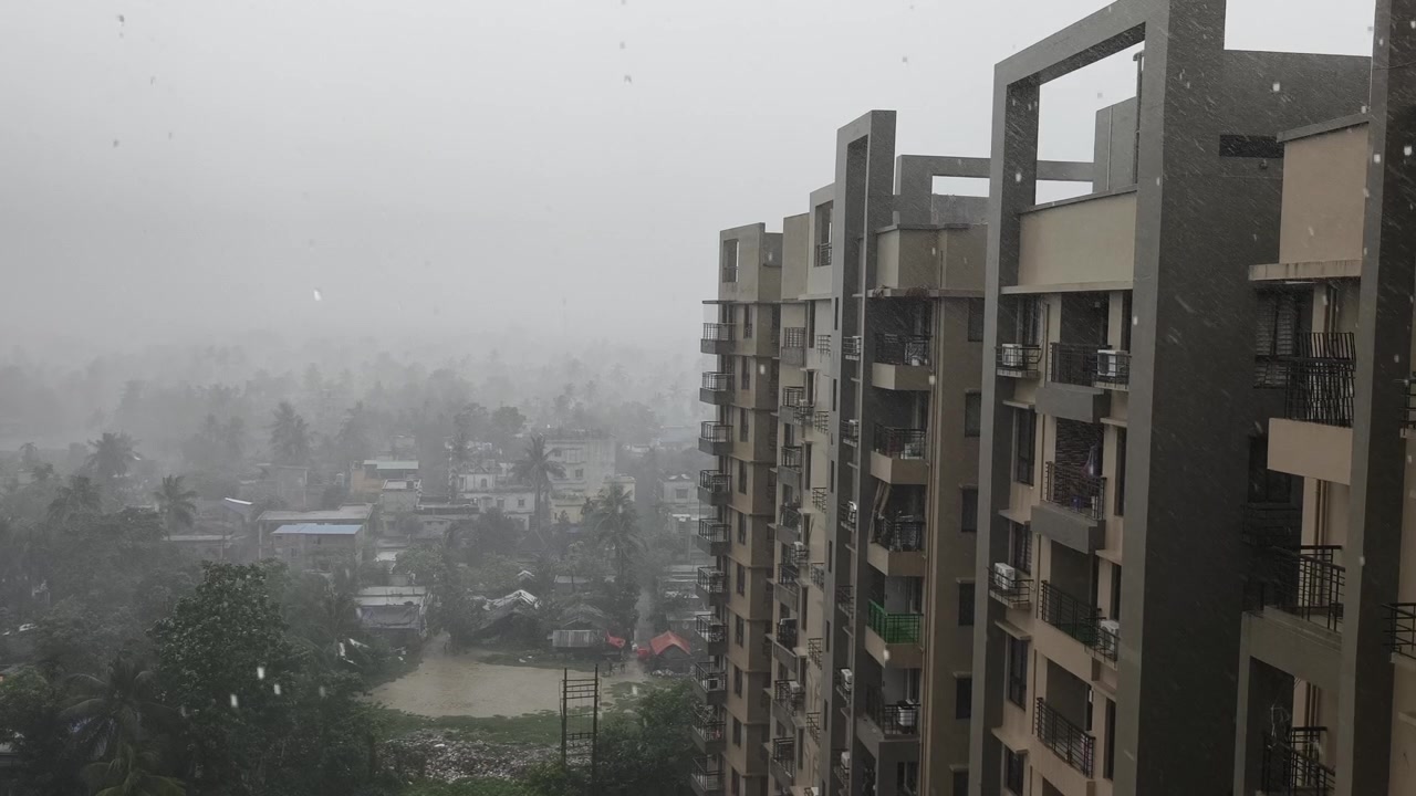 Uma vista de ângulo alto de chuva intensa de monções sobre um complexo de apartamentos residenciais e uma exuberante cidade tropical na Índia. Perfeito para relatórios meteorológicos ou documentários sobre o clima.