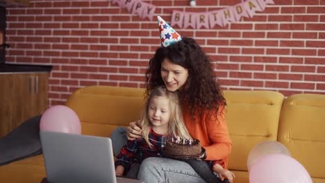 Mutter-Sitzt-Mit-Ihrer-Tochter-Im-Vorschulalter-In-Geburtstagsmützen-Und-Führt-Einen-Videoanruf-Per-Laptop