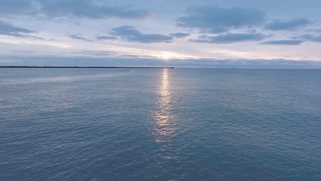 hermosa vista aérea que establece las ruinas de la fortificación de la costa de hormigón de karosta, vibrante puesta de sol de alto contraste sobre el tranquilo mar báltico, noche de invierno, amplia toma de drones moviéndose hacia atrás