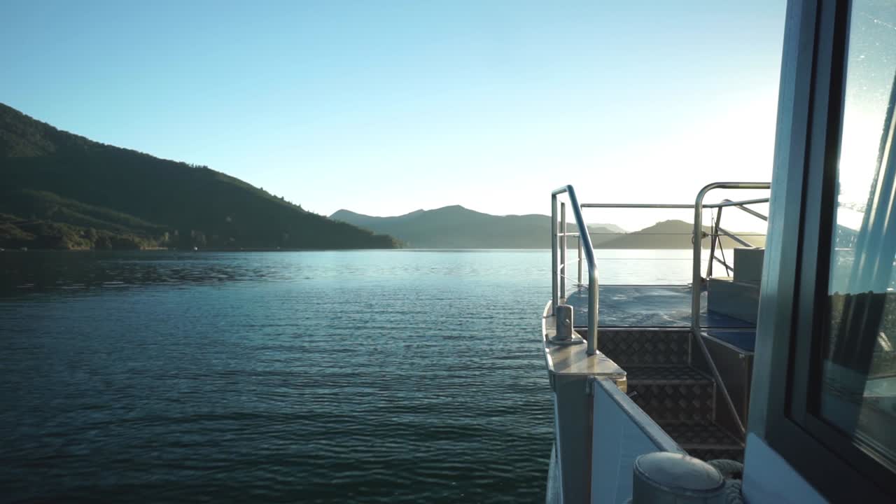 Morgendliche Bootsfahrt bei Sonnenaufgang in den Marlborough Sounds, Neuseeland, mit Bergen im Hintergrund