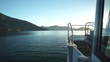 Morning-sunrise-boat-ride-in-Marlborough-Sounds,-New-Zealand-with-mountains-in-background