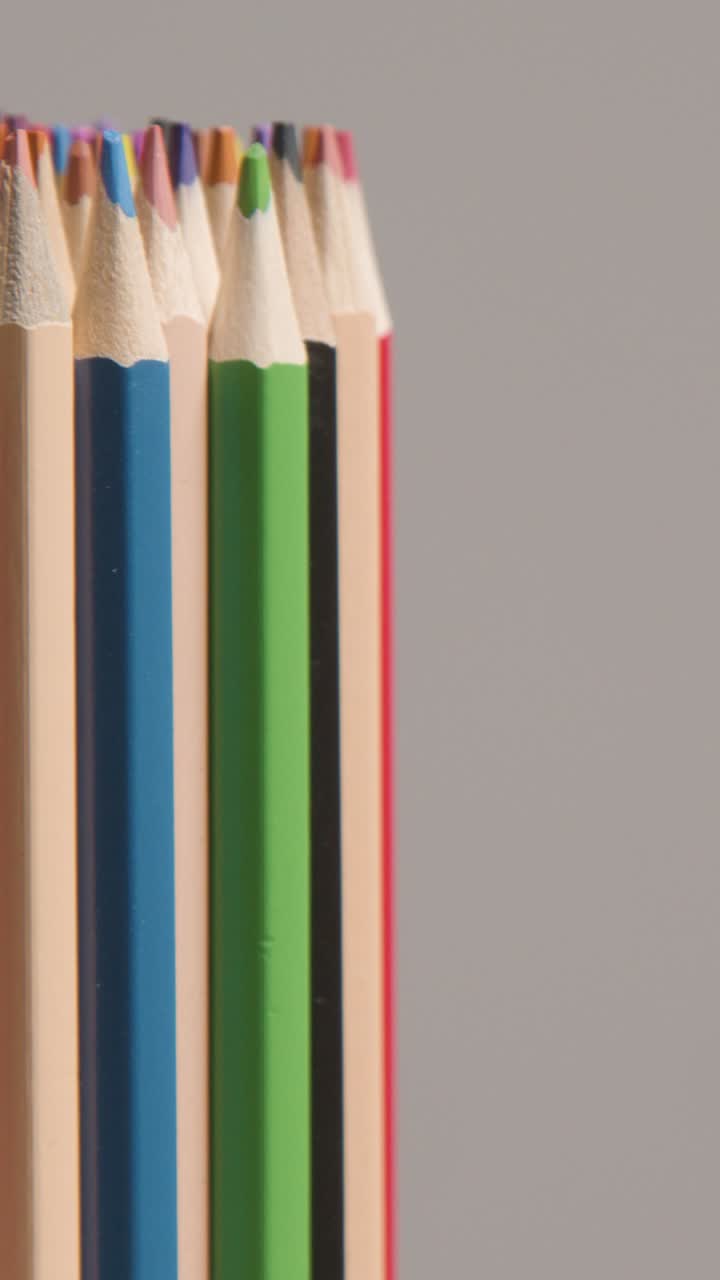 disparo vertical de estudio de vídeo de lápices giratorios multicolores contra un fondo gris