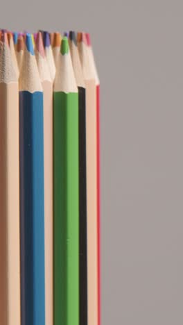 disparo vertical de estudio de vídeo de lápices giratorios multicolores contra un fondo gris
