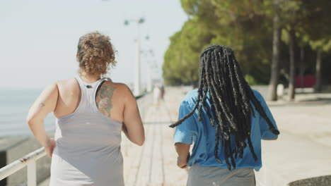 vista trasera de amigos caucásicos y estadounidenses corriendo en el parque