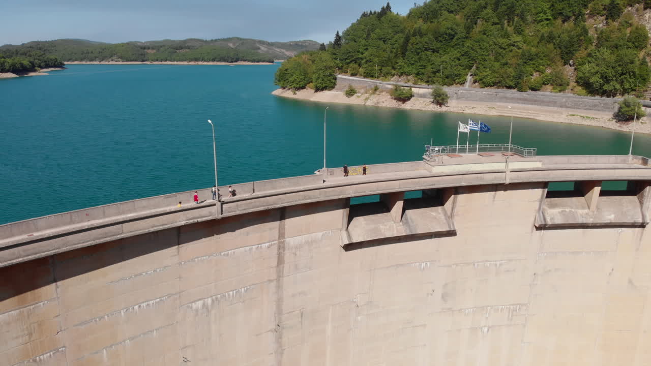 People walking on Curved road on top lake Plastiras hydro electric dam Greece