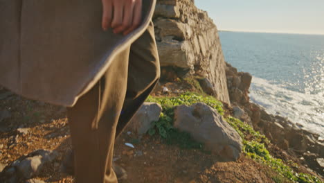 closeup man legs walking rocky hill. pensive tourist contemplating ocean nature