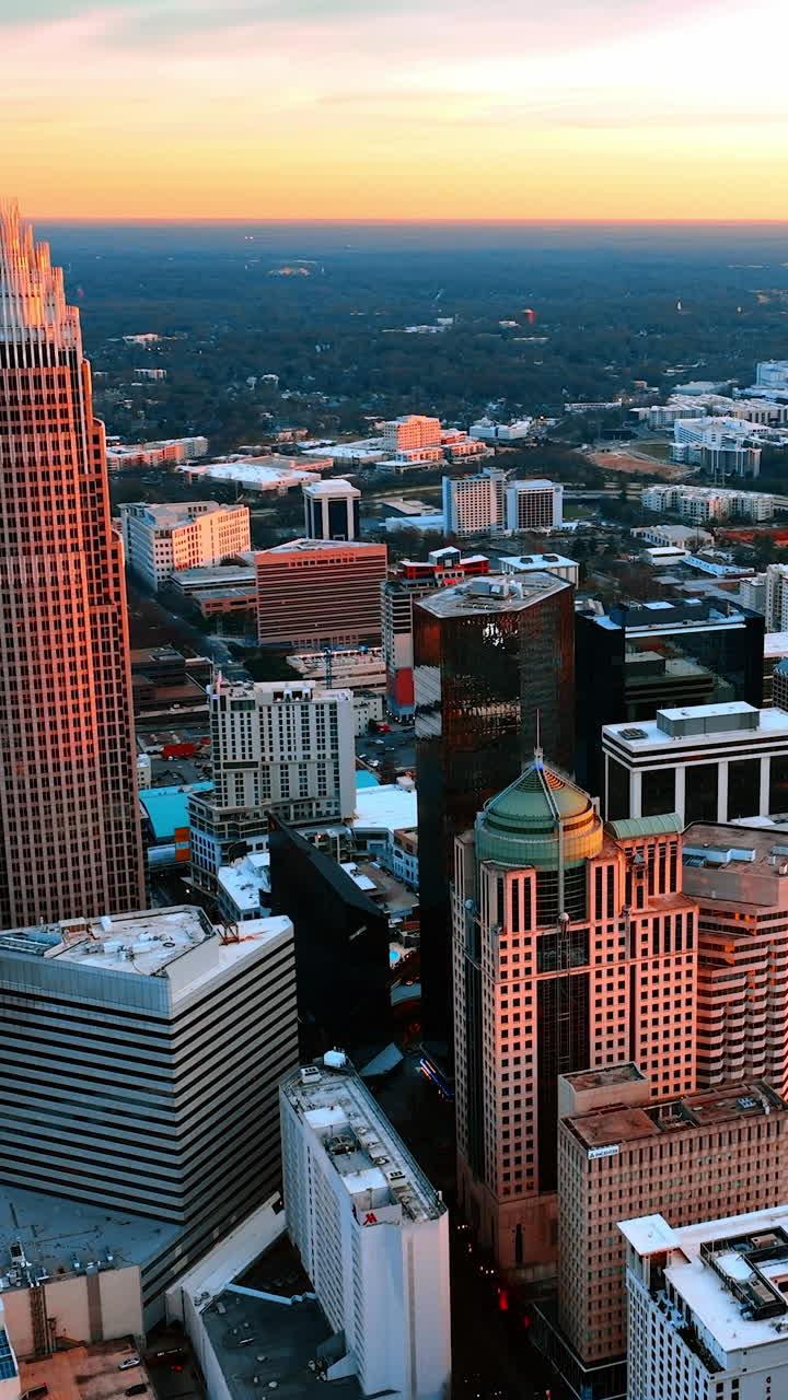 Edifici illuminati di luce arancione al tramonto nella zona residenziale della città. Vista dall'alto del panorama della città americana di Charlotte, Carolina del Nord, USA. Video verticale