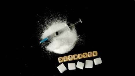 jeringa cayendo en una pila de azúcar además de dados deletreando diabetes y cubos de azúcar