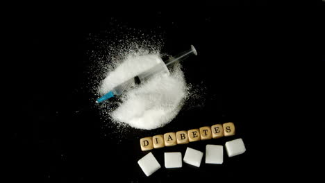 syringe falling into pile of sugar besides dice spelling out diabetes and sugar cubes