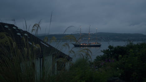 tall ship in bay, seen behind houses. coastal scene in scotland