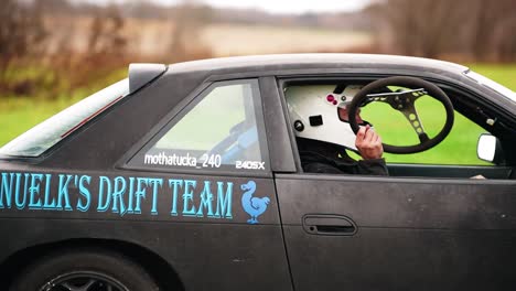 race-pilot-rising-a-steering-wheel-through-window-before-racing-at-Great-Lakes-Dragaway-in-Wisconsin-USA