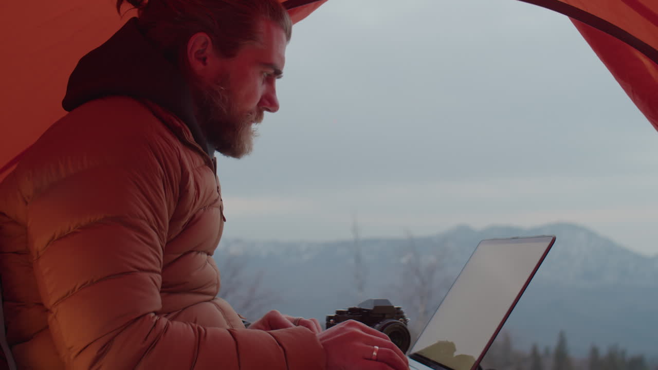 Photographer Using Laptop in Tent on Mountain Top