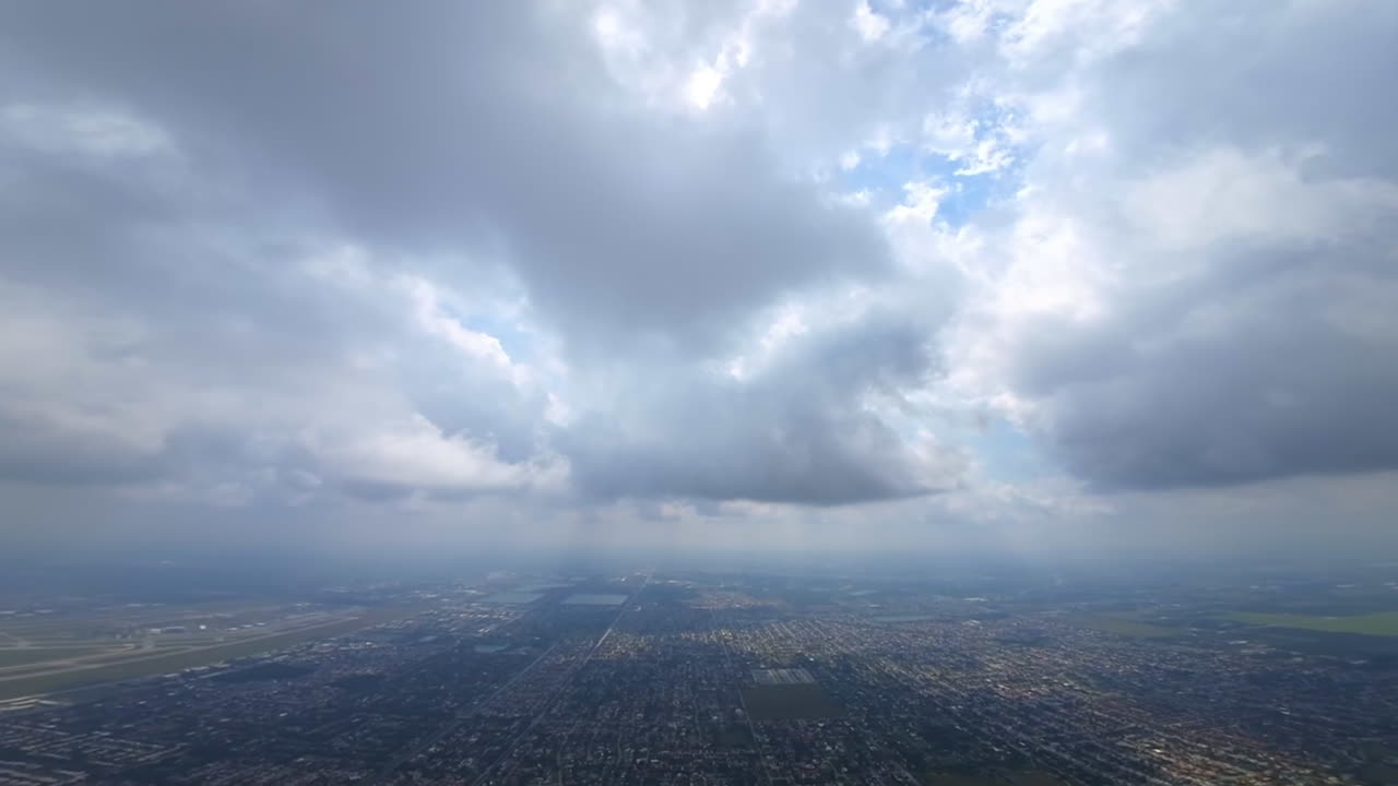 FPV drone footage below the cloudscape high above the urban territory. Drone rises into the cloud and strives to the sun.