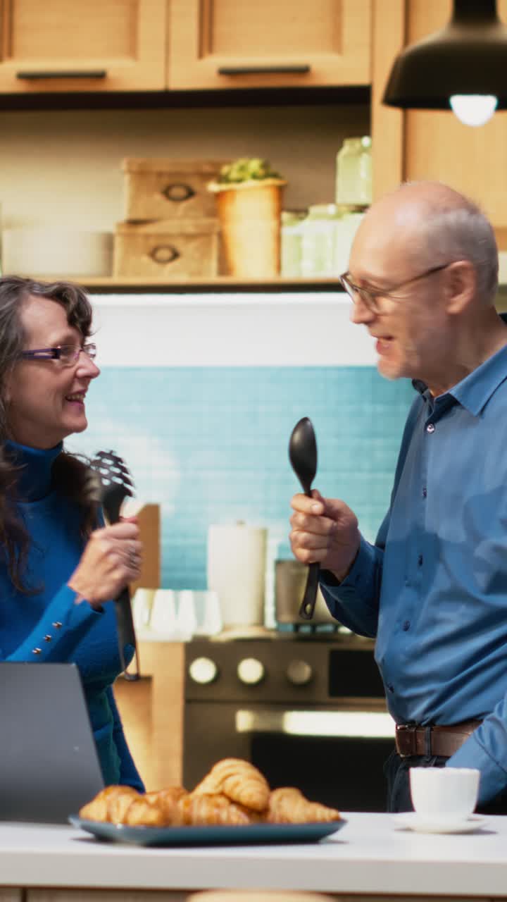 Video verticale Coppia sposata anziana felicissima che canta al karaoke e si sente giovane in cucina