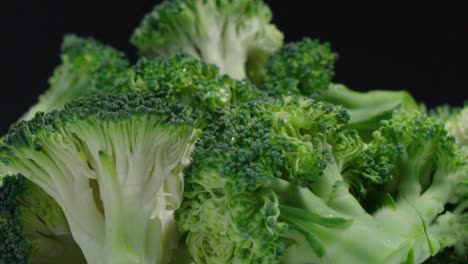 stukjes broccoli roteren op zwarte achtergrond, close-up detail shot