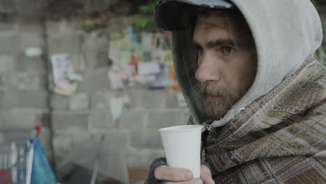 homeless man drinking from a cup on the street