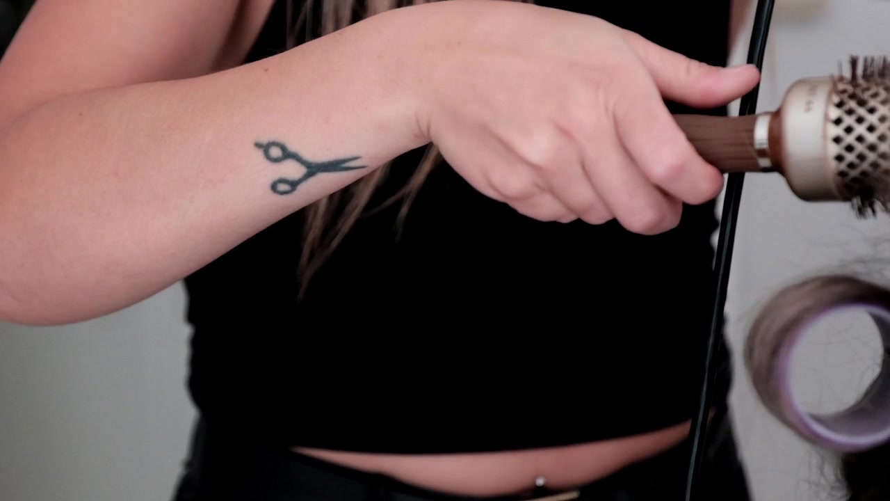 Parrucchiere con tatuaggio a forbice al lavoro.