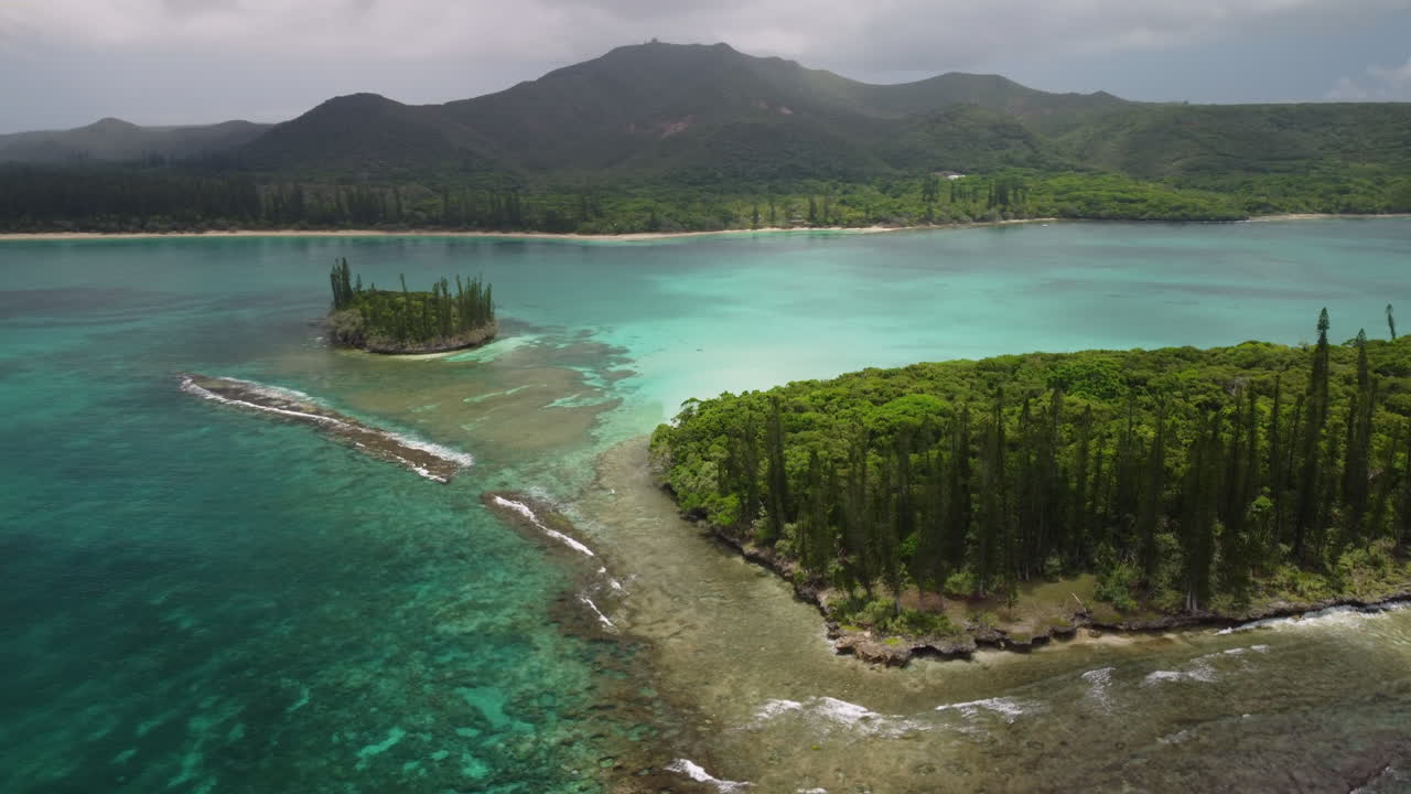 arco aéreo sobre aguas turquesas e islas pequeñas, pico n'ga al fondo, isla de pinos