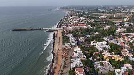 establishing a video shot reveals puducherry's beautiful beach and sprawling urban area. the moody, overcast sky creates a dramatic scene of city meets sea