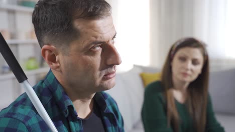 un hombre ciego con un bastón le dice a su esposa su problema.