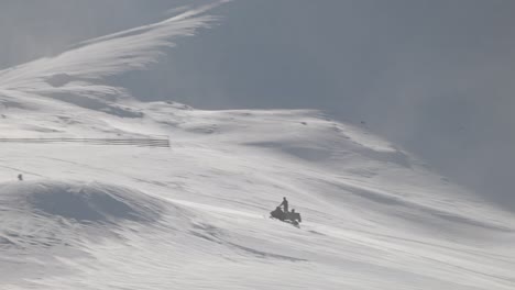 Snowmobile-driver-fast-on-uphill-slope-toward-snow-maker