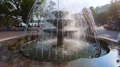 Beautiful-fountain-in-Hanoi-in-the-Old-Quarter-Vietnam-filmed-in-120fps-in-a-pan-up-motion-with-scooter-driving-by