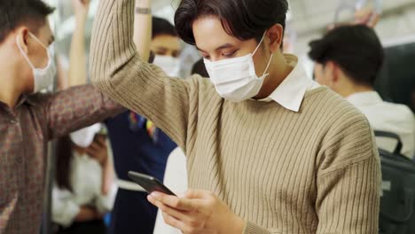 viajero que usa una máscara facial mientras usa un teléfono móvil en un tren público