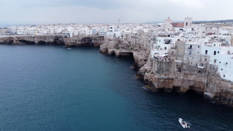 vista de drones, vuelo pasando por casas en acantilados marinos, polignano a mare