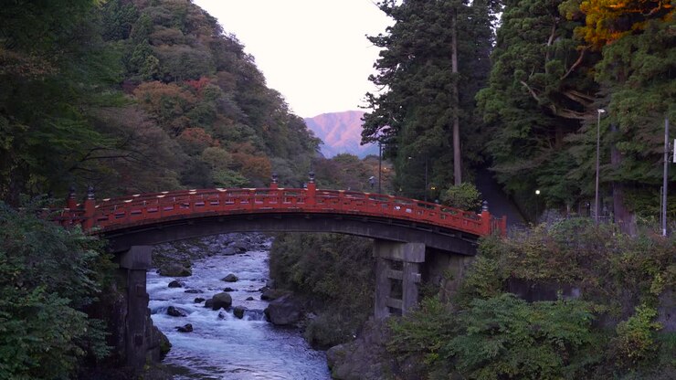 Vista tranquilla del Ponte Shinkyo a Nikko con il fiume che scorre sotto e auto che passano