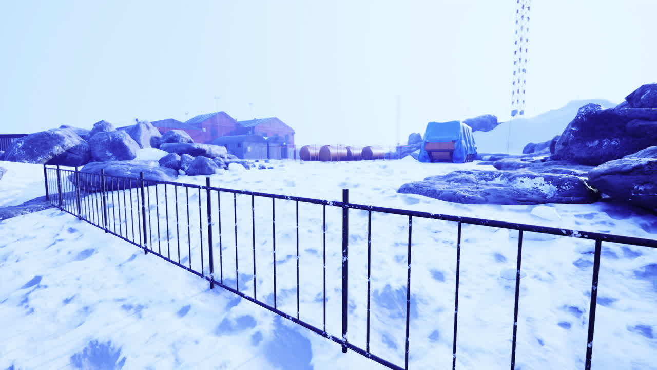 Snowy landscape with rocks and buildings in a remote location during winter